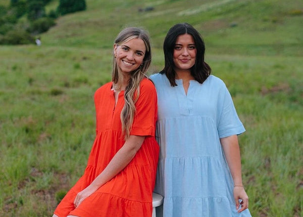 Two women wearing Called to Surf dresses in a field