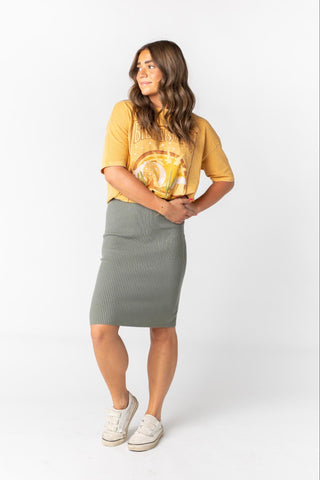  A woman poses in a midi olive skirt
