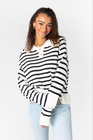A woman poses in a black and white striped sweater