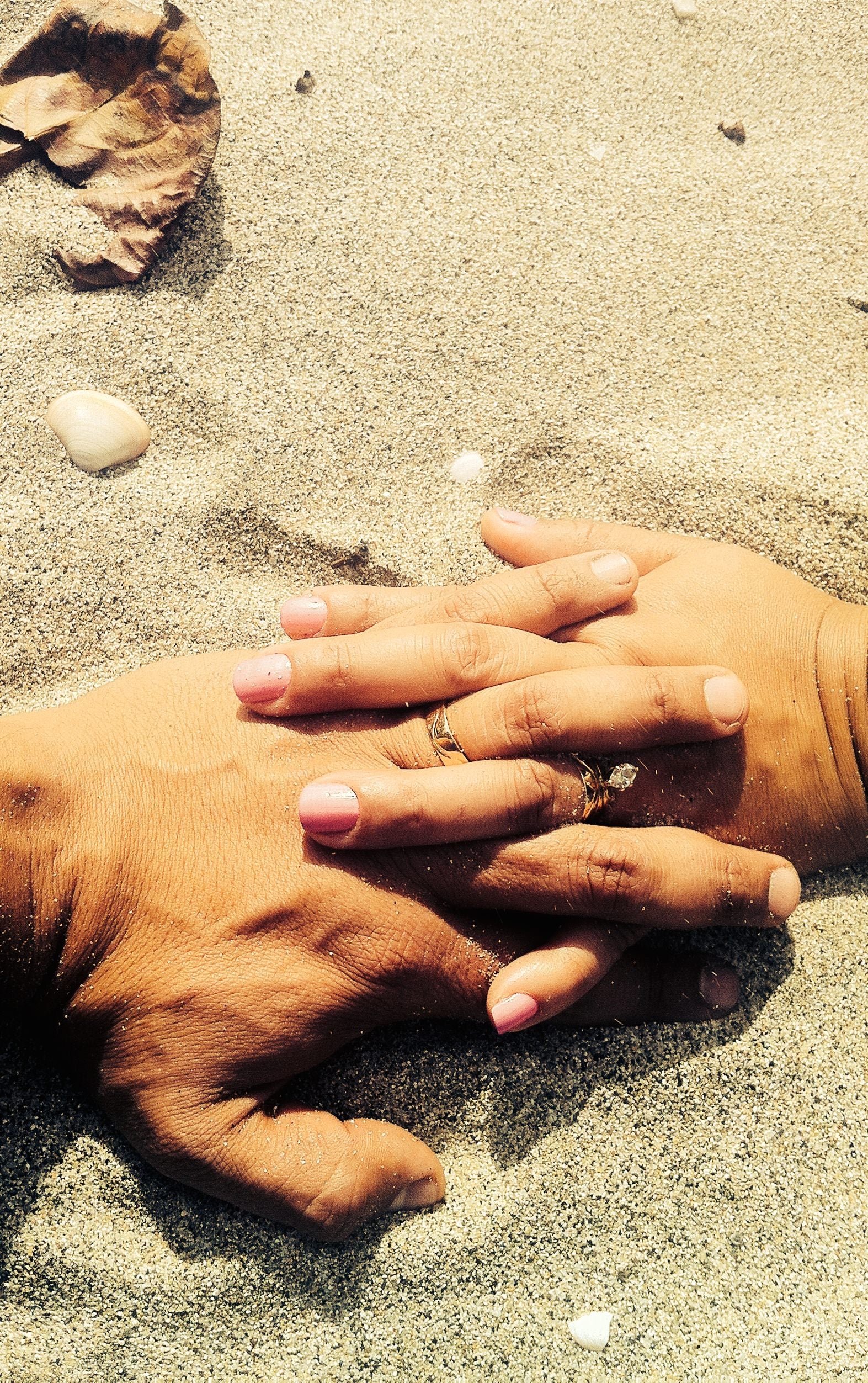 close up of a couple holding hands on a beach