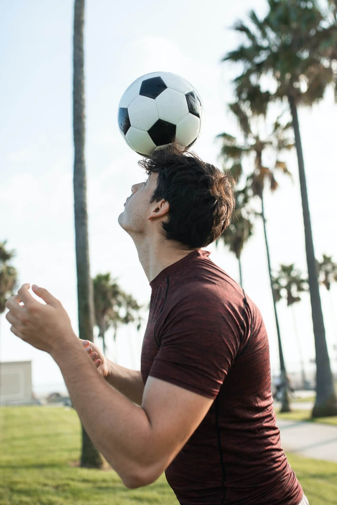 male soccer player with soccer ball on head