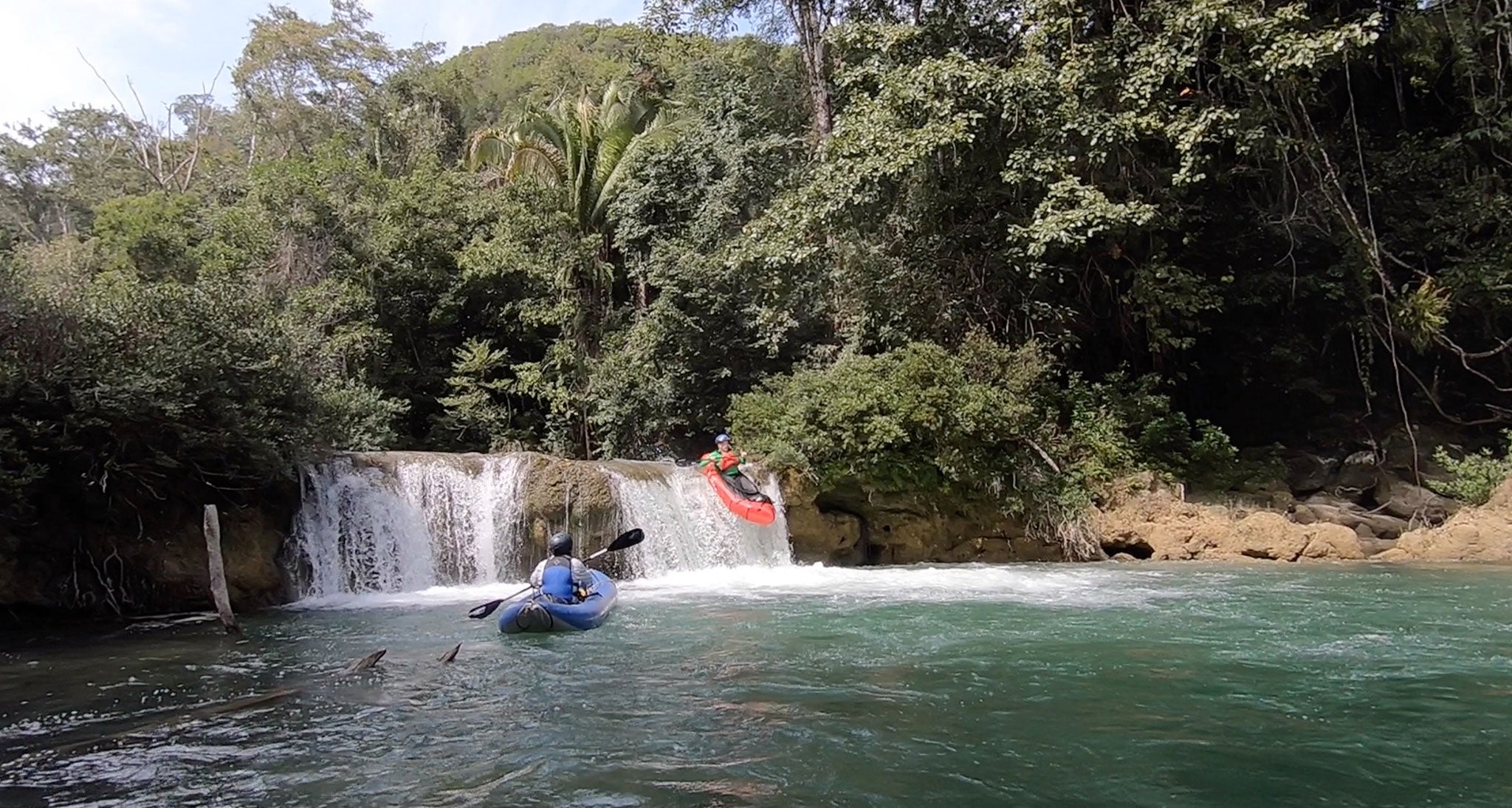 Kayaker cresting a small waterfall in the river