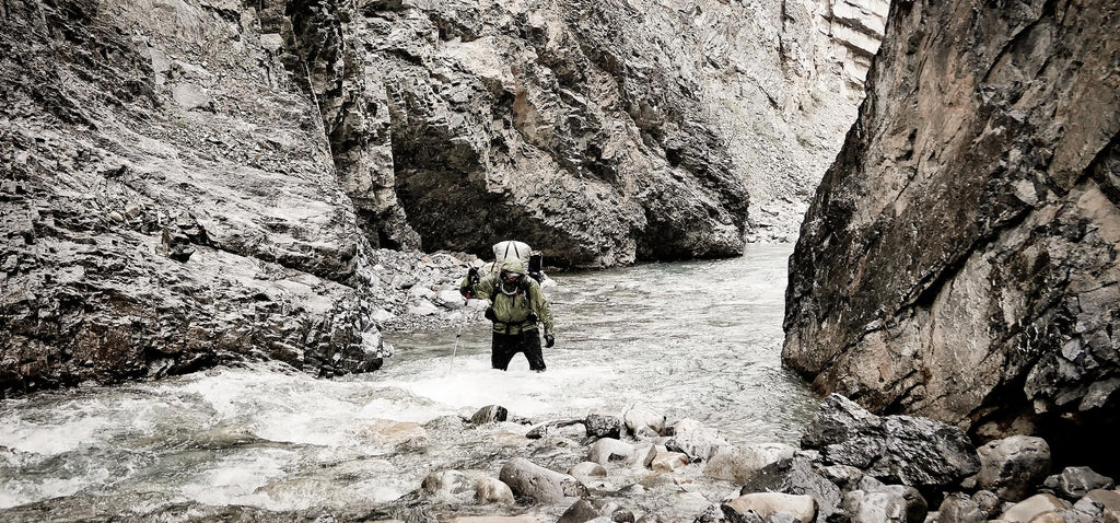 Ultralight backpacker wading through deep water