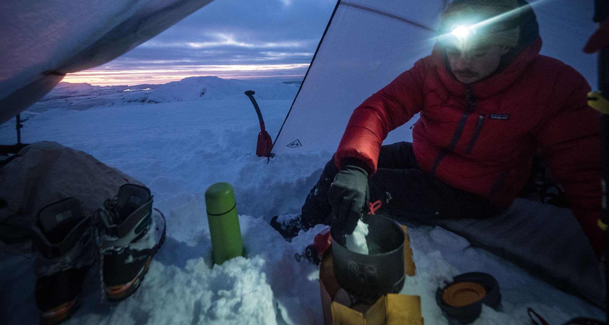 Alpinist in the tent boiling snow into potable water