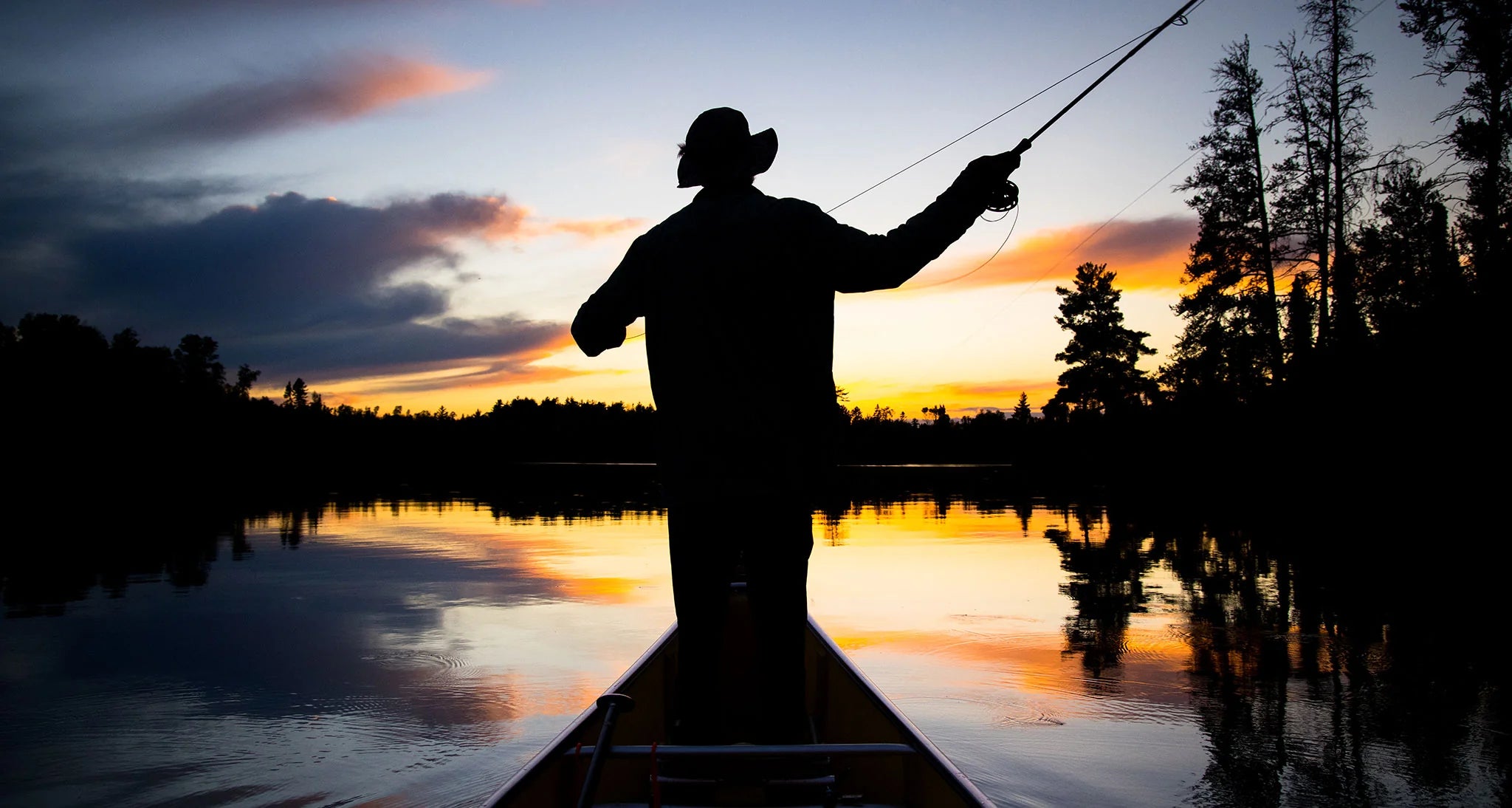 fishing from a canoe at sunset