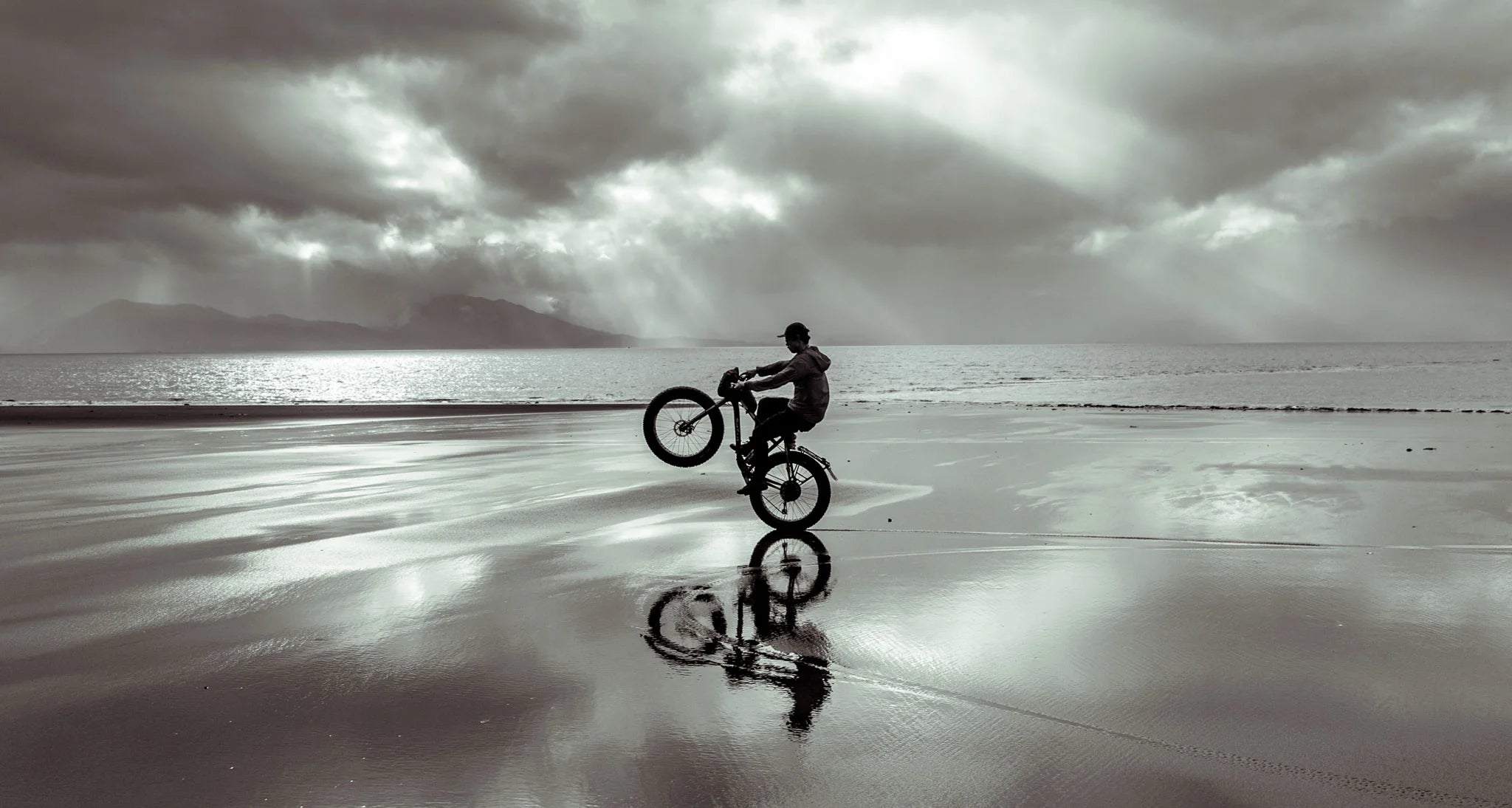 fatbike wheelie on the wet beach sand