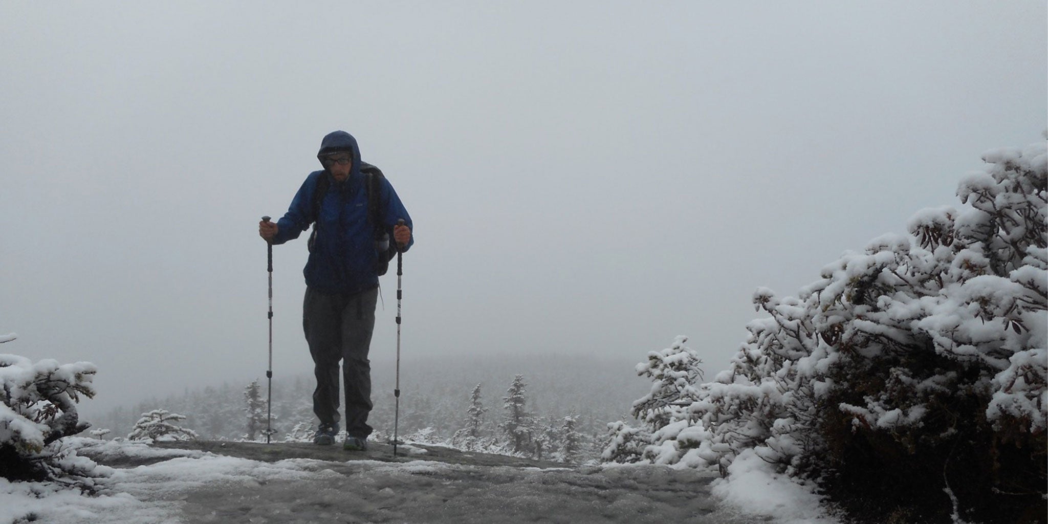 Freezing hiker crests the snowy hill