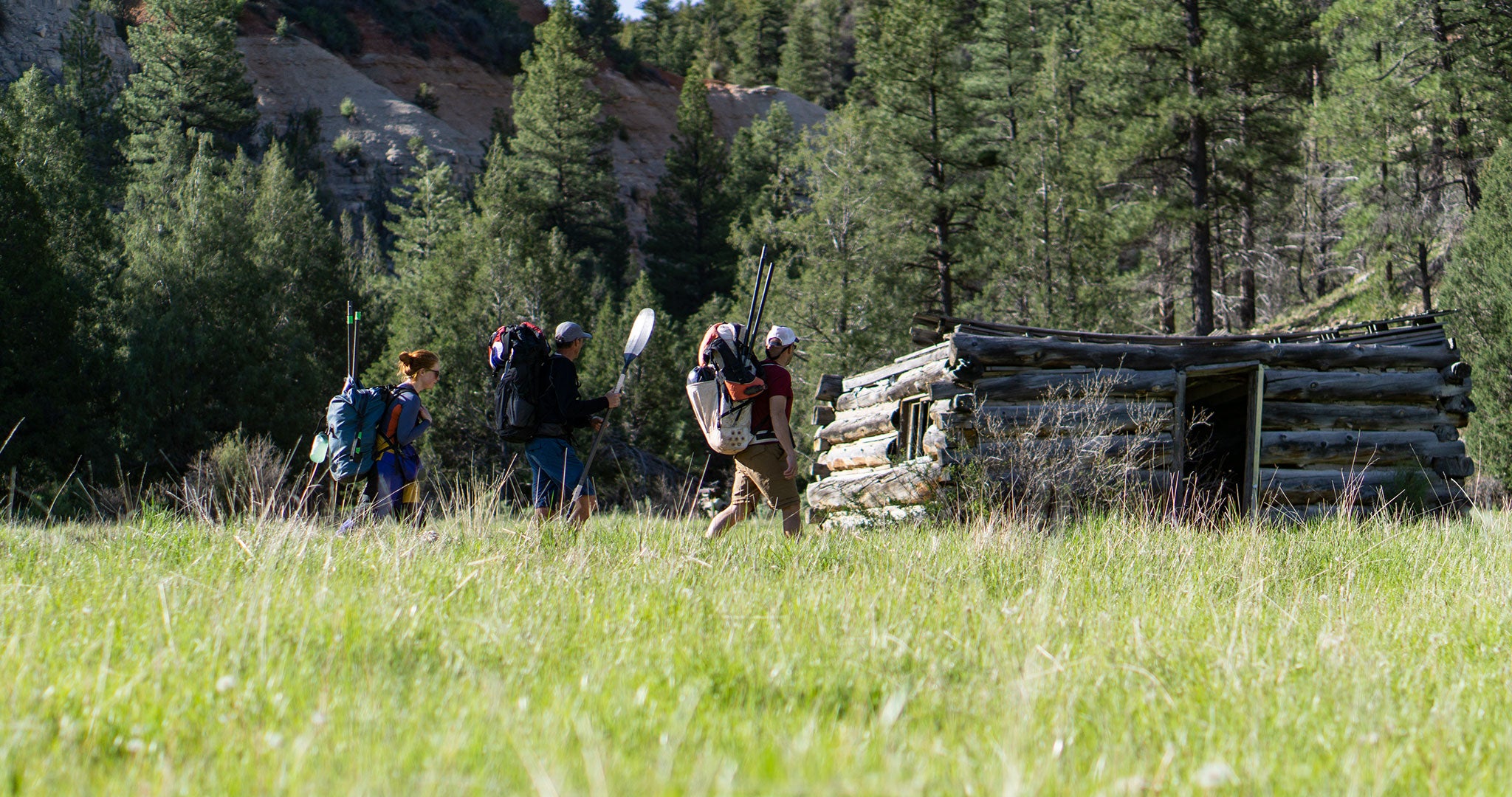 Ultralight backcountry packrafters walking through grass