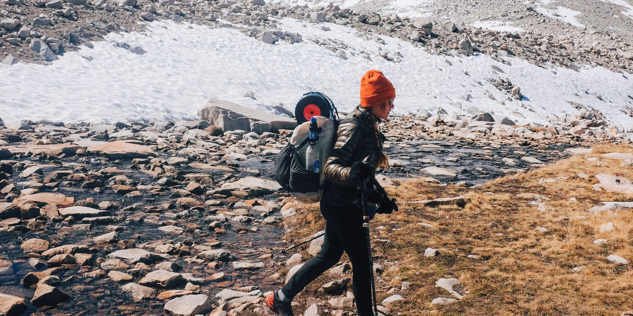 Hiker crossing a snowy river bed