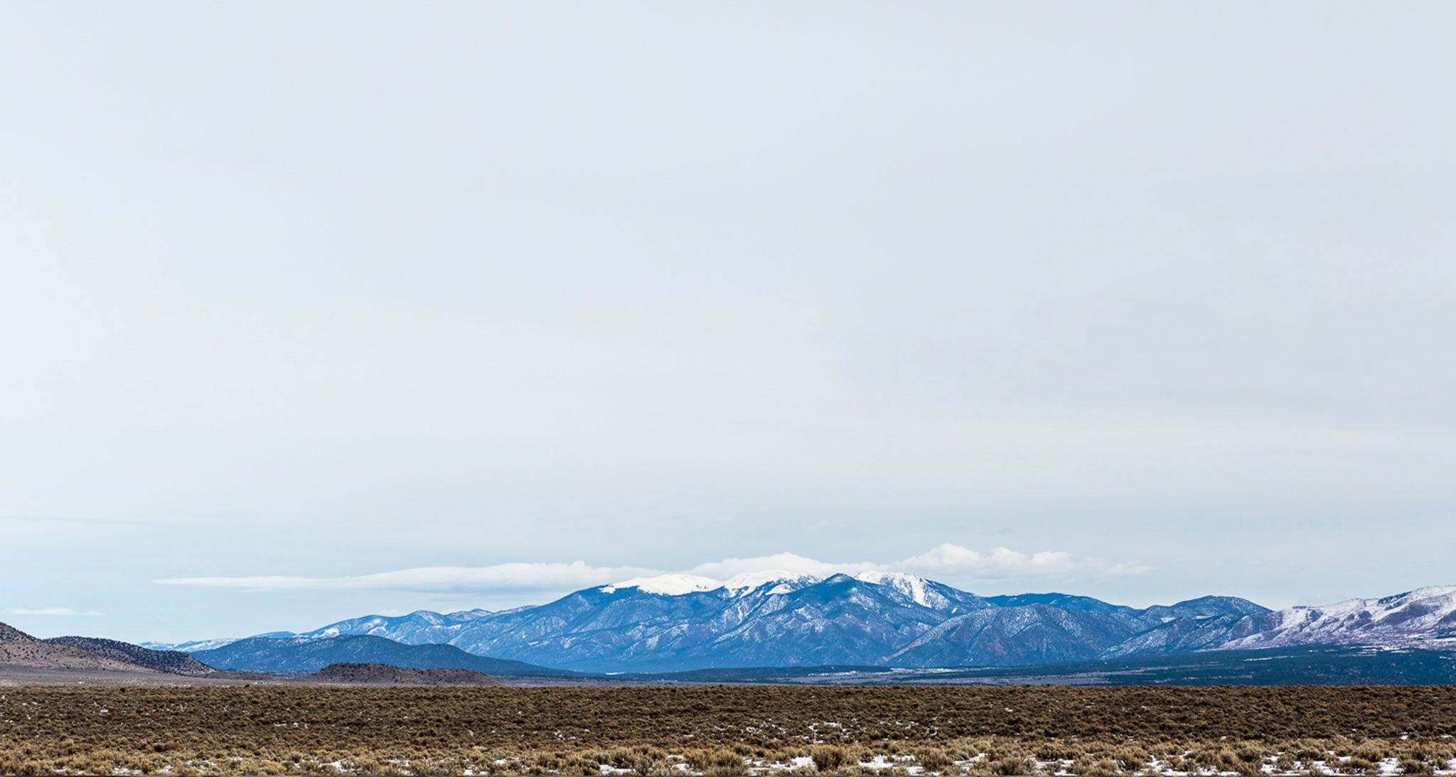 This is the second stage of nimbostratus development with cirrostratus clouds in the highest levels of the atmosphere continuing to thicken from the top down into very high level altostratus clouds near 15000 feet above the Rio Grande Valley in northern New Mexico.  There is a very shallow and small deck of stratocumulus clouds hugging the peaks but those are insignificant.  The higher featureless cloud deck covering most of the sky started as cirrostratus and is gradually thickening and lowering into the mid levels of the atmosphere.  This alone doesn't mean rain is coming but is sure is an indicator worth watching.