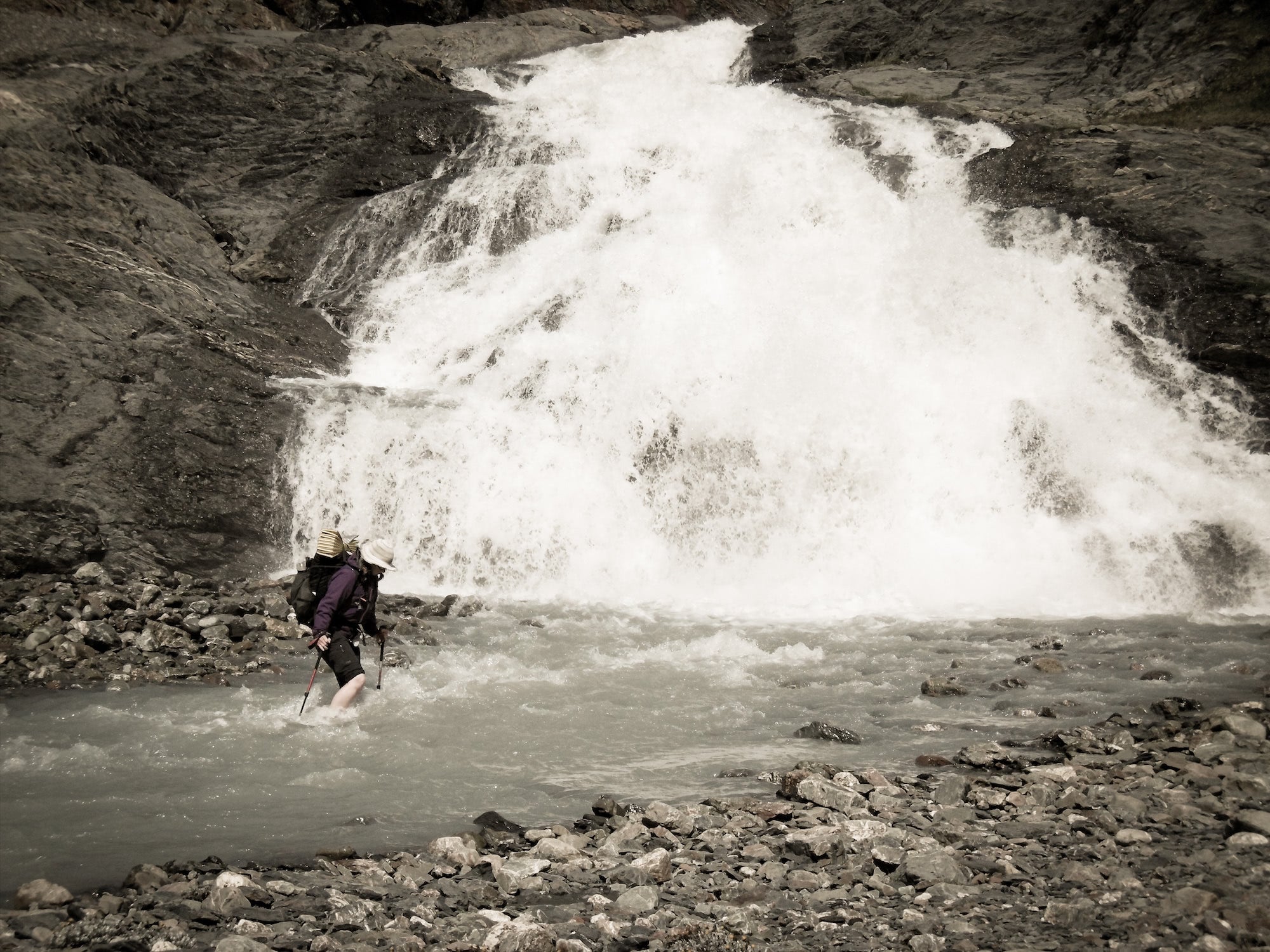 Ultralight backpacker crossing a fast river on foot