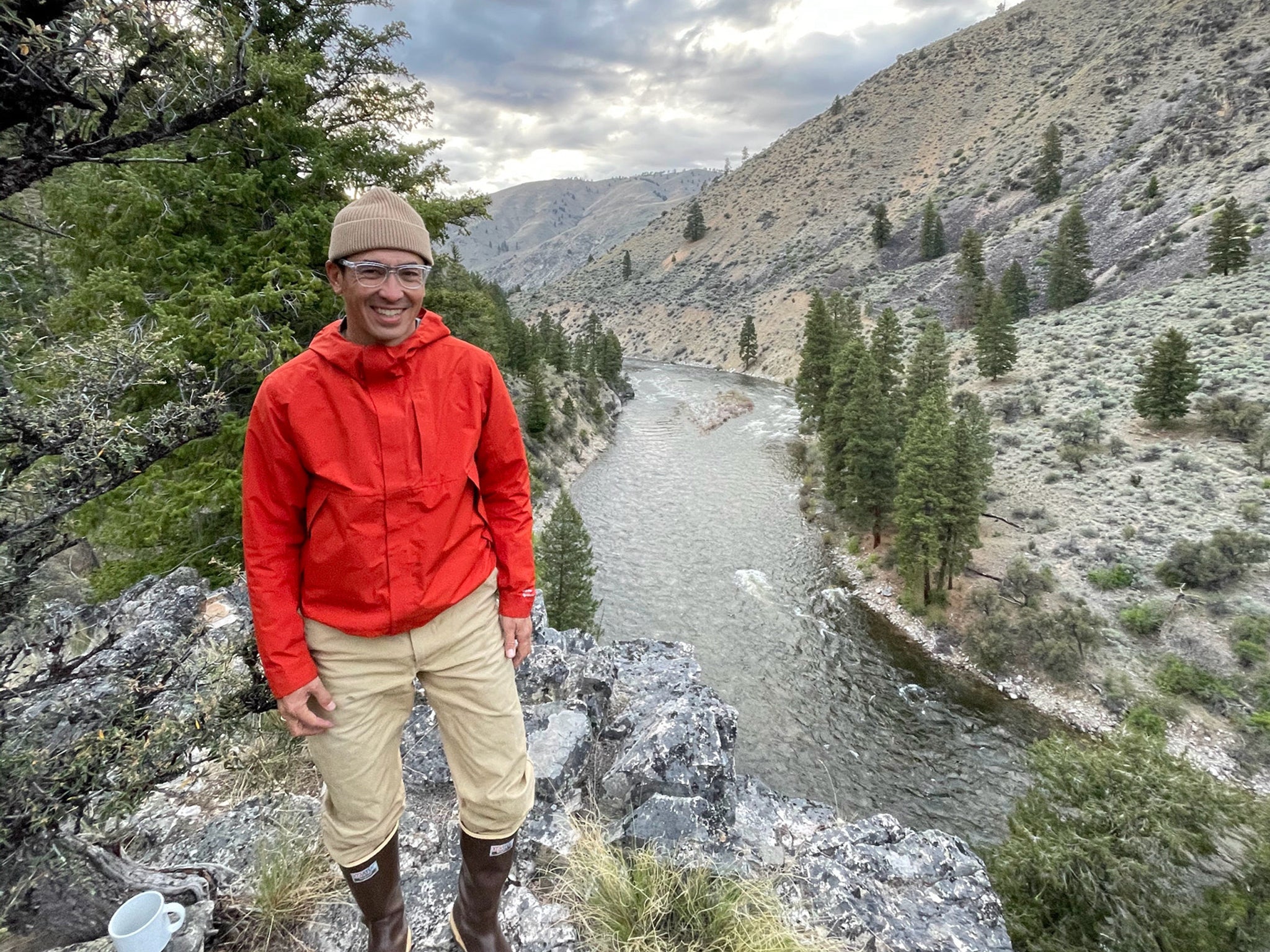 Hiker stands on a cliff overlooking the river below