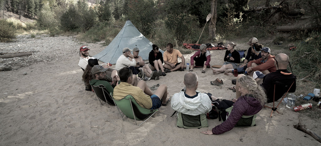 Group of backpackers sit in a circle outdoors
