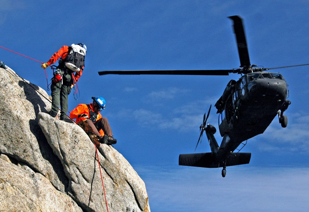 Two climbers rock climbing with helicopter above