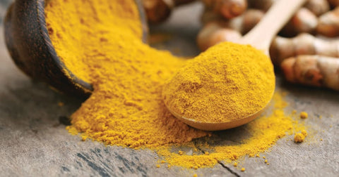 Powdered curcumin, with turmeric roots in the background, to show how it's normally eaten