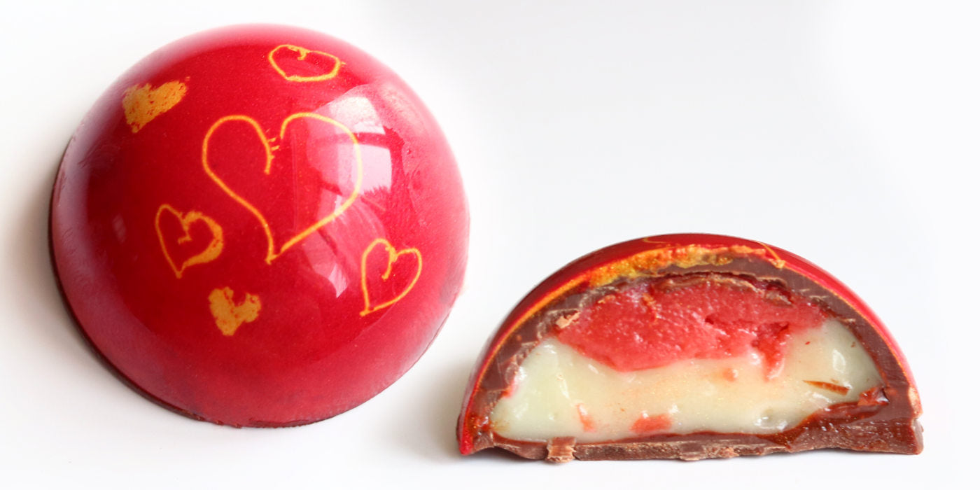 White chocolate bonbon sample with custom-designed outer (left), and showing strawberry ganache filling (right)