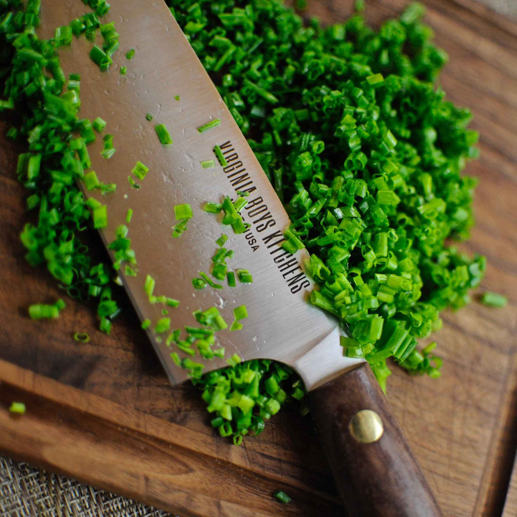 close-up of a Virginia Boys Kitchen brand knife cutting spring onion