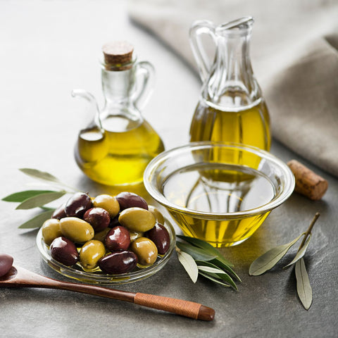 olive oil in containers and also olives on a small dish on a table