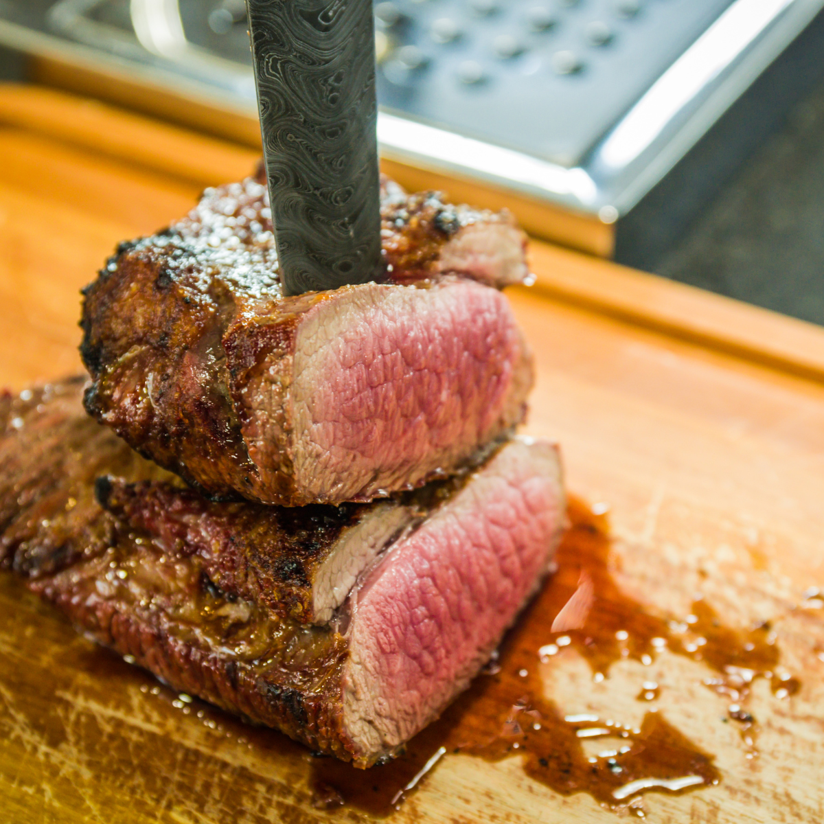 steak sliced in half on top of a cutting board with a knife through it