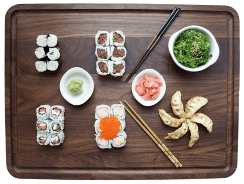 assorted sushi and chopsticks on a black walnut cutting board