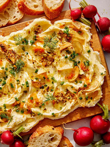 butter board with garlic, crushed nuts, chives, dill, orange zest