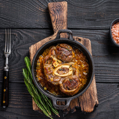 cast iron cooking meat on a wooden cutting board