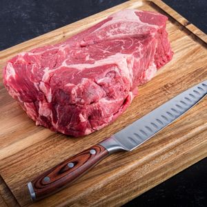 raw chuck roast on a wood cutting board with a knife