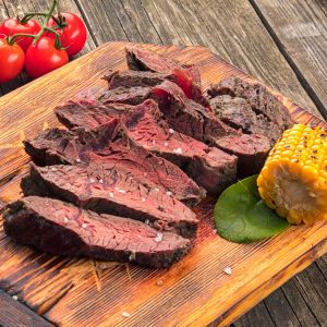 cooked hanger steak sliced with tomatoes and grilled corn on the side