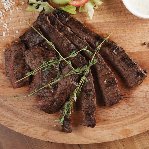 cooked skirt steak on a wooden cutting board