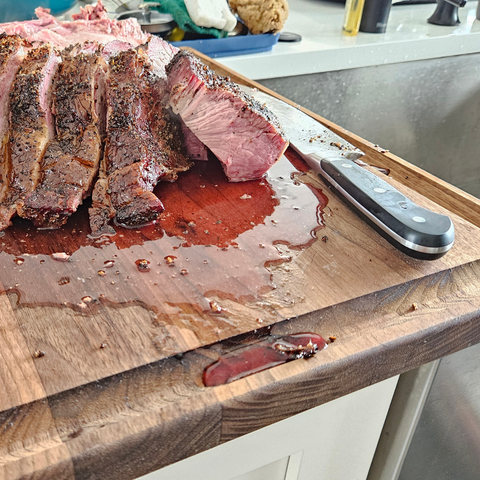 cutting board extra large with rib roast cut up on it, juice of the rib dripping into the juice well from the cutting board