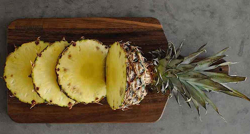 sliced pineapple on a black walnut cutting board