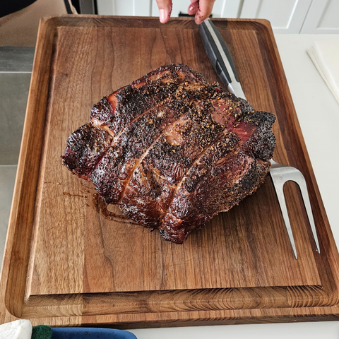 prime rib roast cooked, on a wooden cutting board with a fork