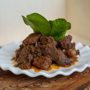 rendang stew on a white plate garnished with leaves