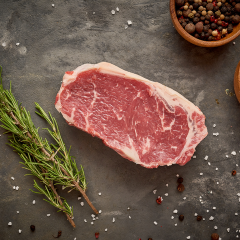 sirloin steak on black background with rosemary and sea salts and pepper in background top view