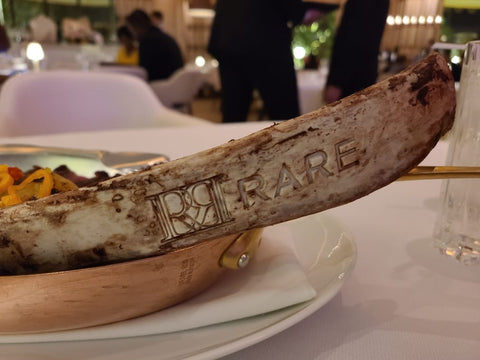 bone from tomahawk steak seared with restaurant logo: RARE STeakhouse