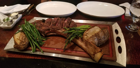 tomahawk steak on large serving tray with asparagus already cut up