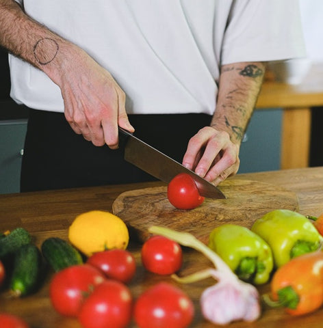 person cutting peppers on wooden cutting board