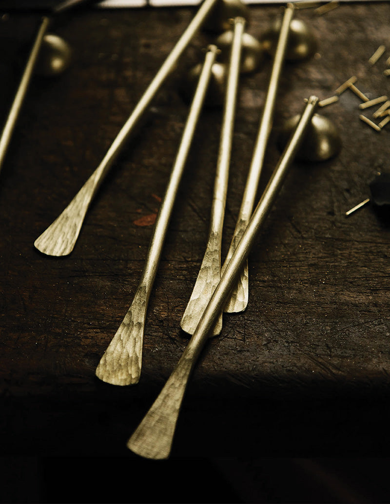 Brass candle snuffers sit waiting to be polished on an antique wooden bench