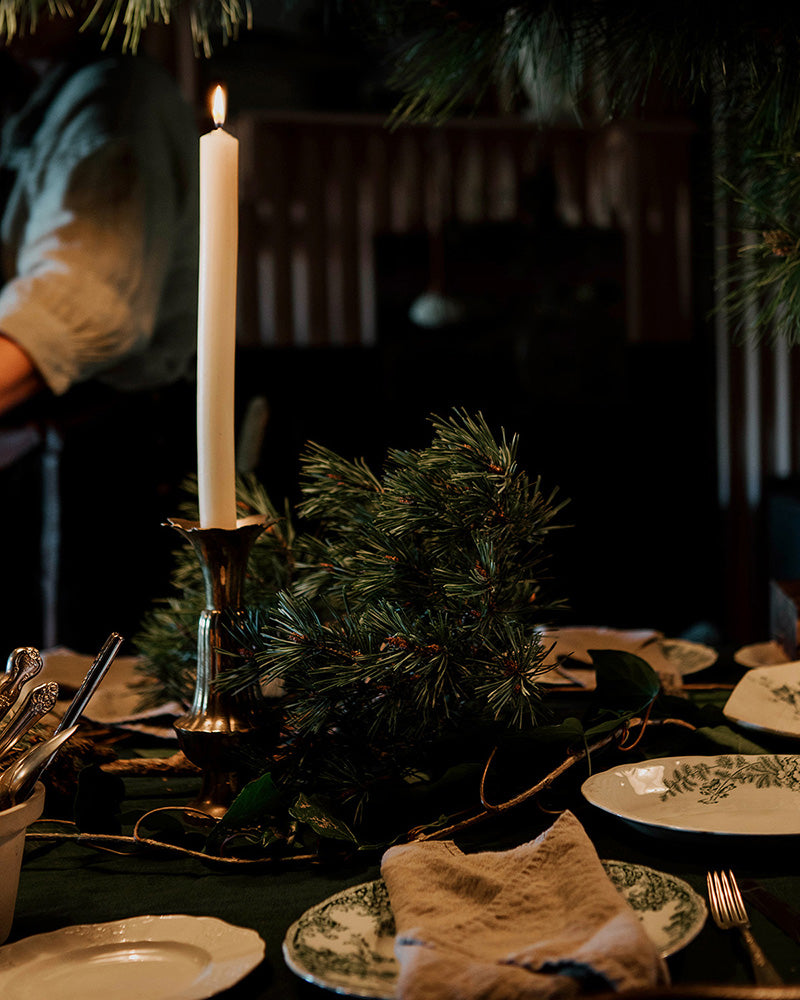 A vintage themed festive table with pine, ivy and brass candlesticks