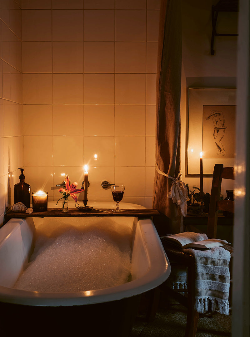 A vintage clawfoot bath lit by candles.