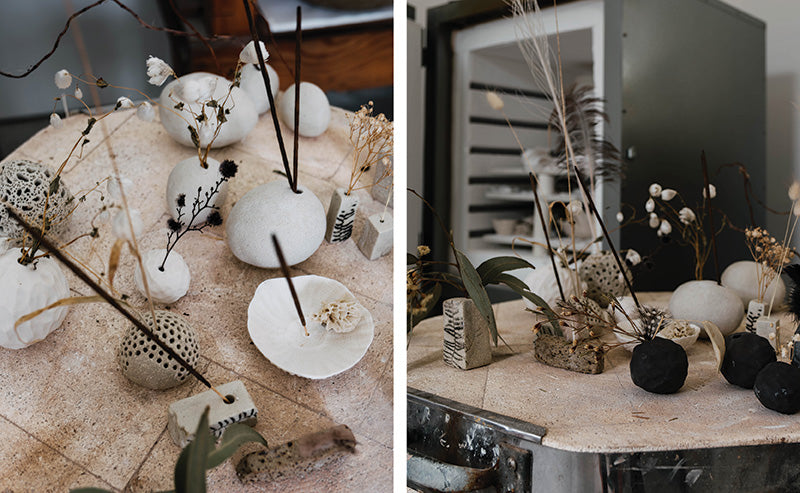 Porcelain artworks by Jo Victoria displayed on a vintage table. There is a firing kiln in the background.