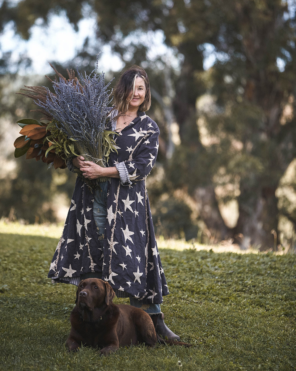 Southern wild co founder Tania Robinson holding a bunch of lavender with her chocolate labrador Boris