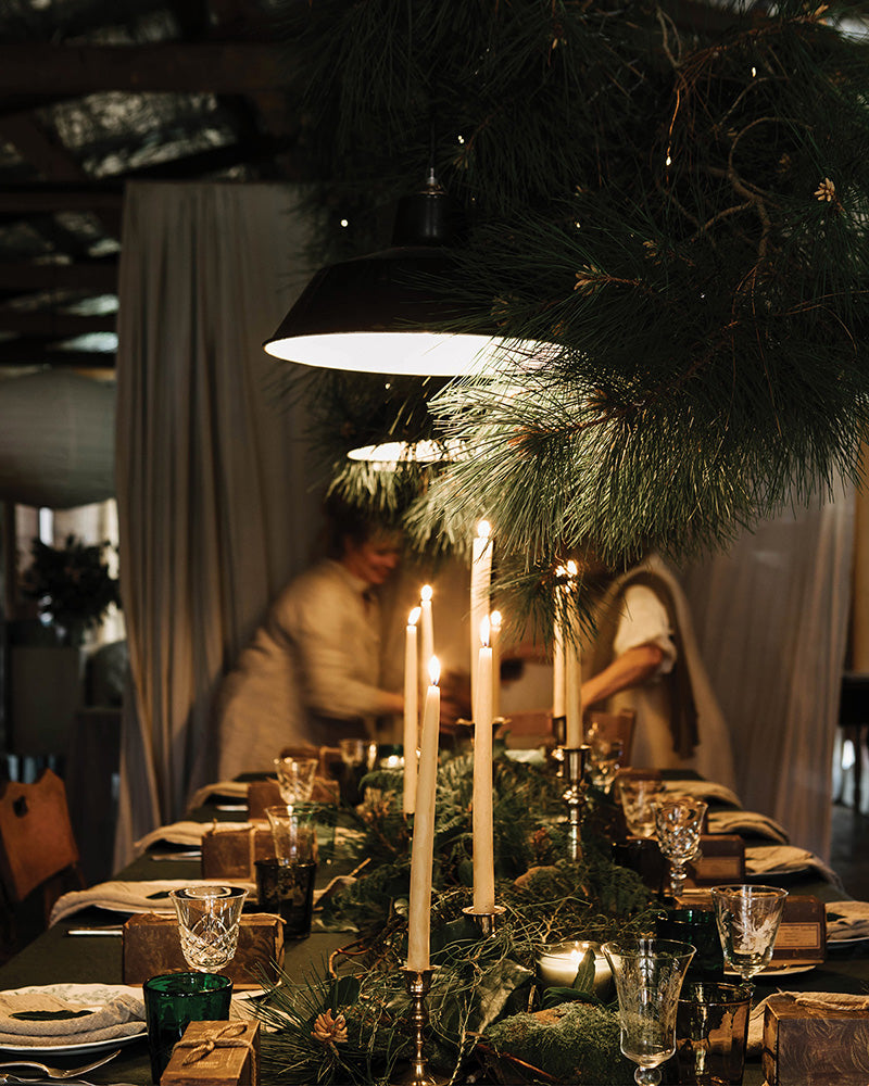 A vintage themed festive table with pine, ivy and brass candlesticks