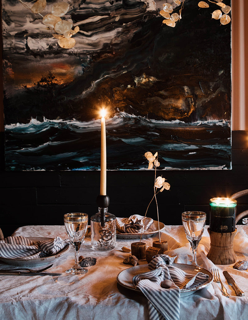 A beach themed tablesetting with vintage tableware, rustic linen and a seascape by Australian artist Paul Ryan on the wall.