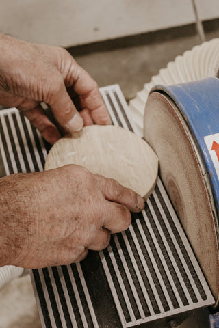 sanding a circular timber disc on bench grinder