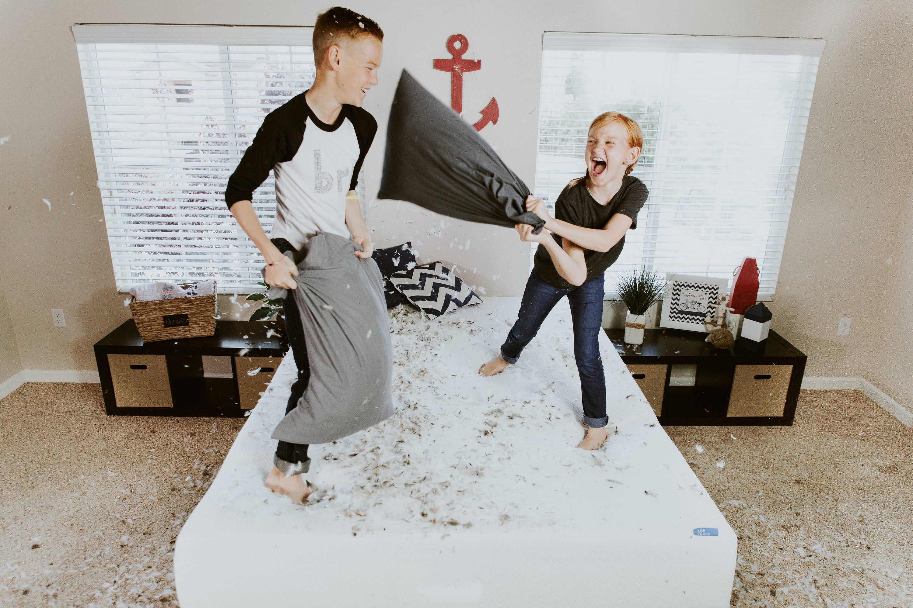 Brother and Sister Jumping on The Bed Having a Pillow Fight - Sibling Photo Idea