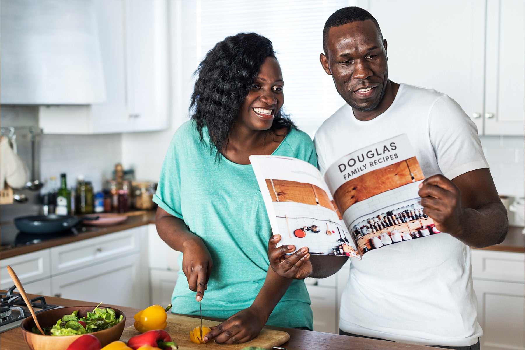 A couple looking at a family photo book cookbook in the kitchen