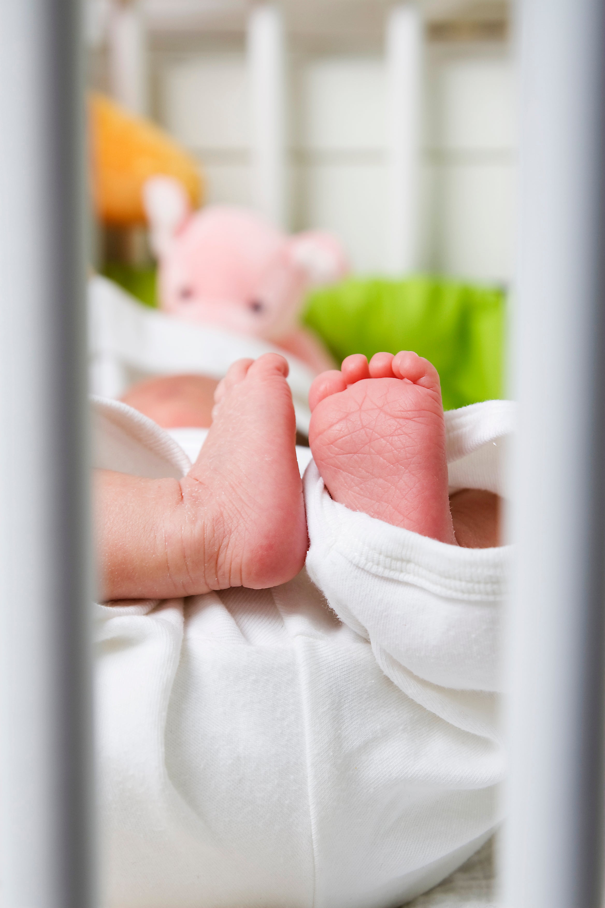 Photo of baby feet seen through the bars of a crib
