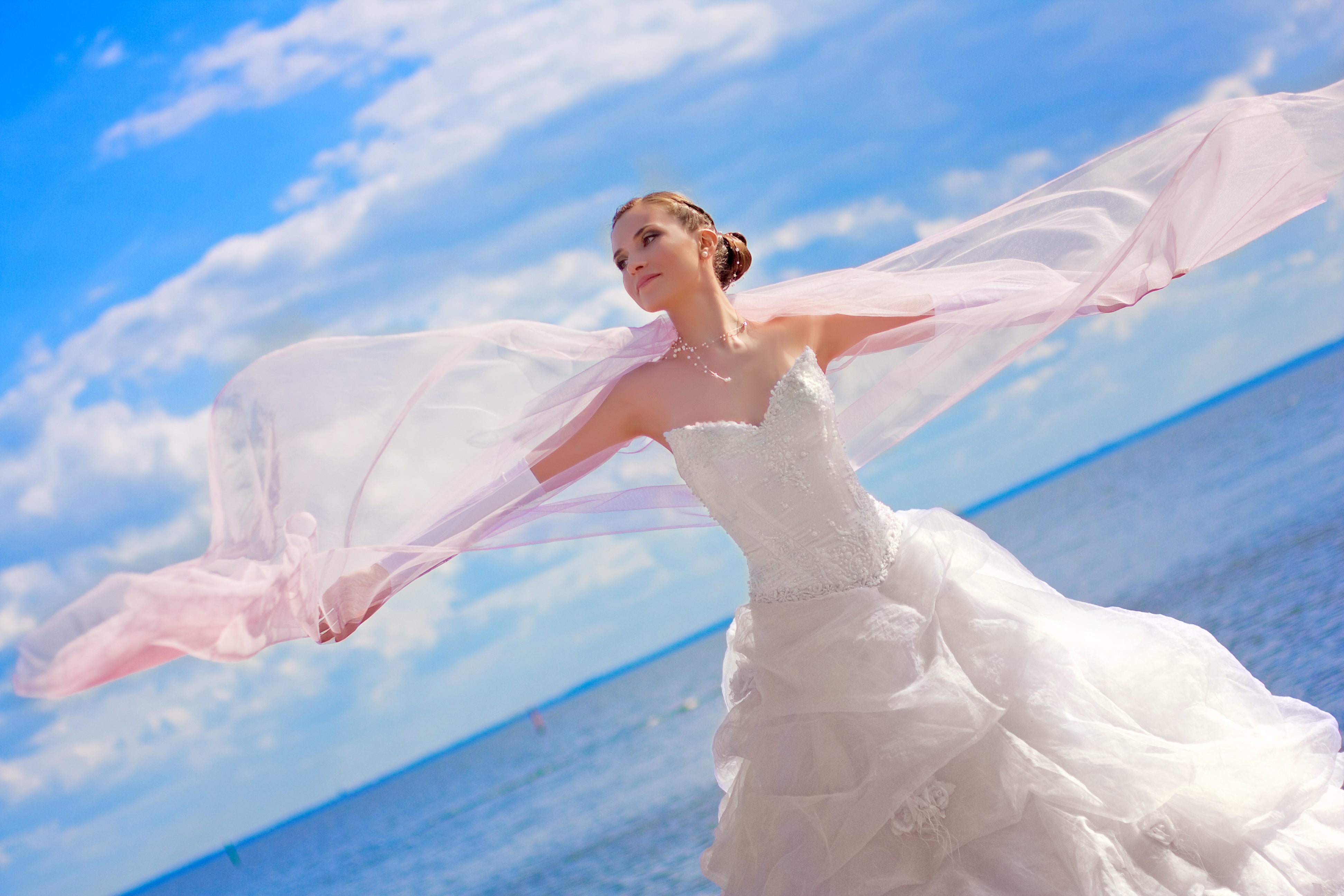 Bride at the ocean with her arms wide open