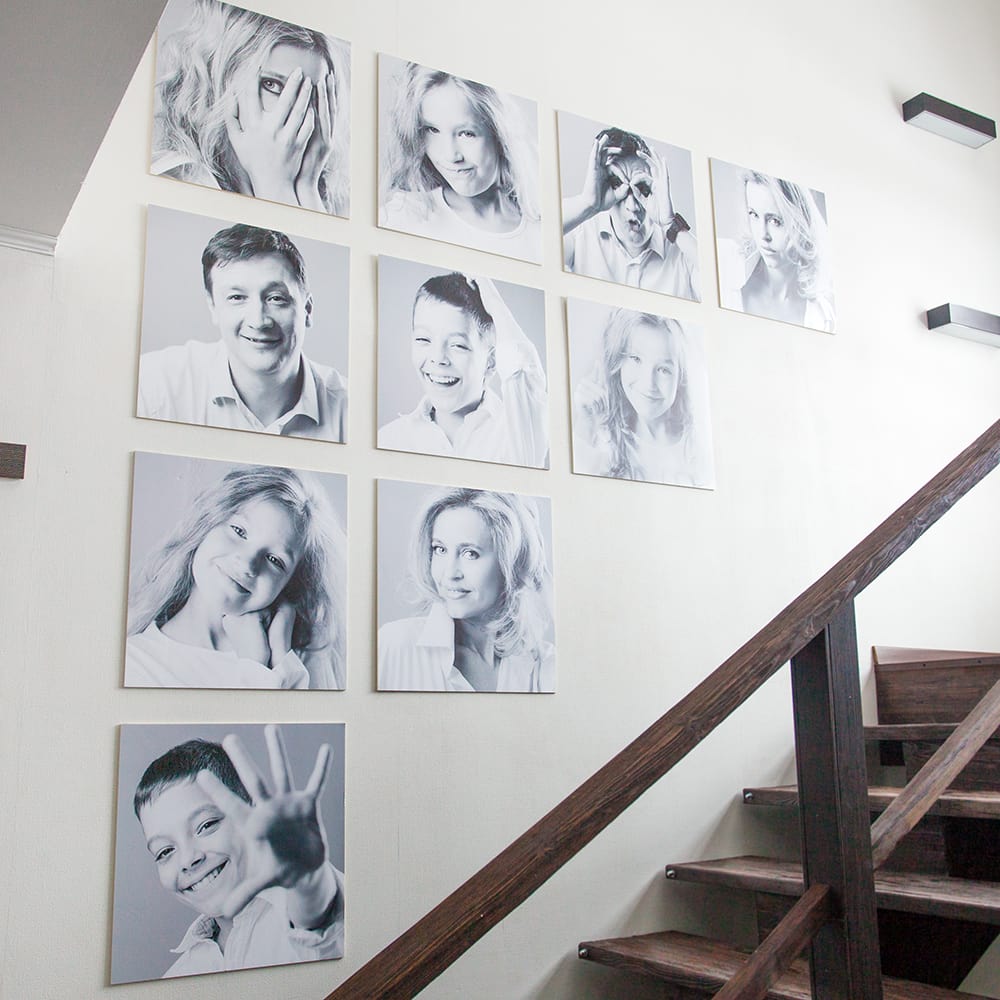 Gallery wall of black and white family portraits displayed on staircase wall
